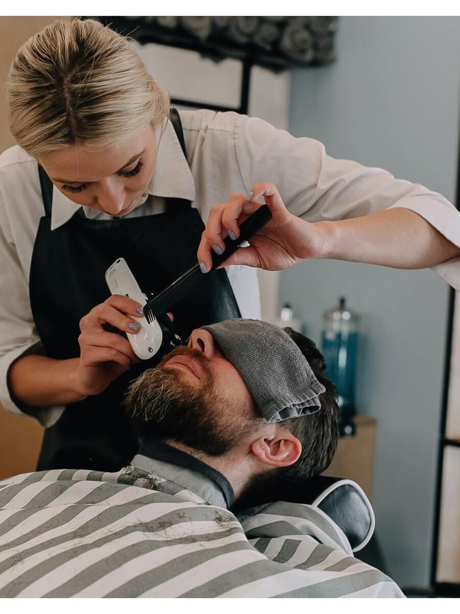Barber trimming a client’s temple with hot towel prep